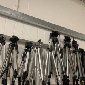 A wall of different types of tripods hanging on the side.