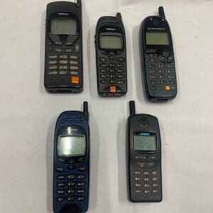 A group of five old cell phones sitting on top of a table.