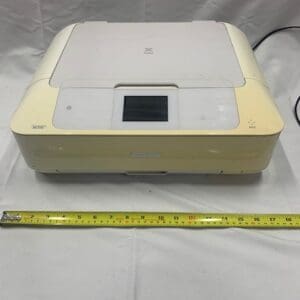 A yellow and white printer sitting on top of a bed.