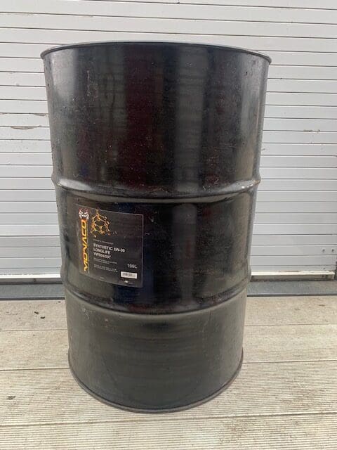 A black barrel sitting on top of the ground.