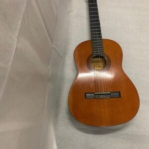 A guitar sitting on top of a white sheet.