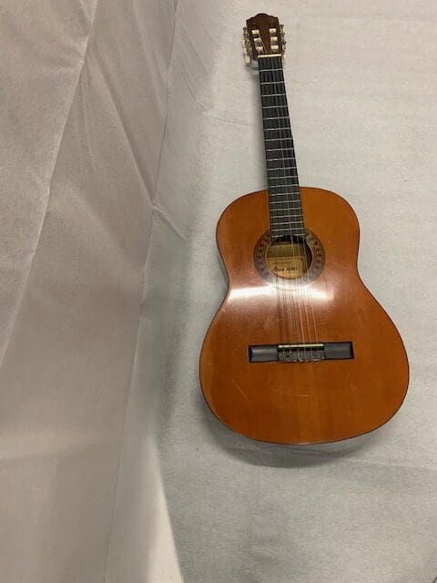 A guitar sitting on top of a white sheet.