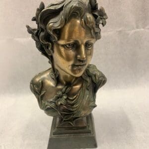 A bronze bust of a woman with flowers in her hair.