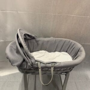 A baby bassinet with a white blanket on top of it.