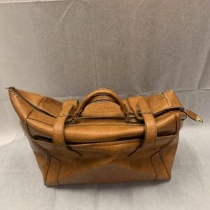 A brown leather bag sitting on top of the floor.