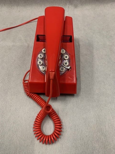 A red phone with an extension cord attached to it.