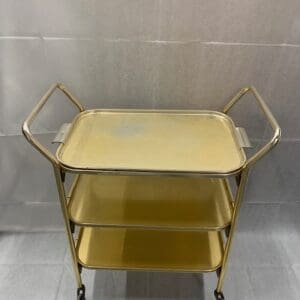 A yellow cart with two handles and three trays.