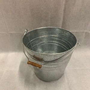 A metal bucket with wooden handles on top of a table.