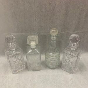 A group of four glass bottles sitting on top of a table.