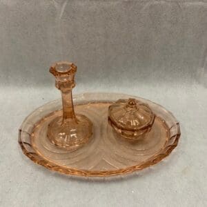 A glass plate with a candle holder and a dish on it.