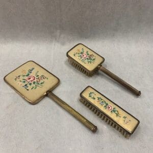 A set of three hand held brushes with floral design.