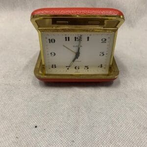 A red and gold clock sitting on top of the floor.