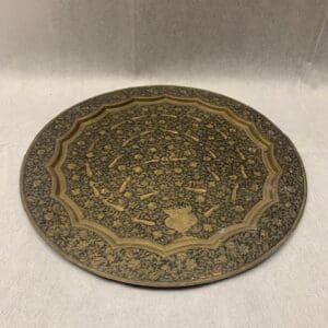 A round brass plate with an intricate design.