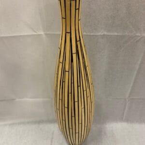 A tall bamboo vase with black lines on it.