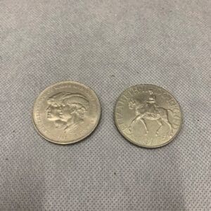 Two silver coins sitting on top of a table.