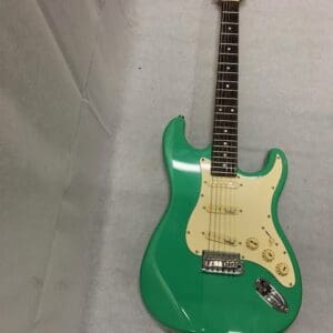 A green electric guitar sitting on top of a white surface.