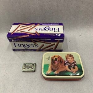 A box of finger foods and a tin with a picture on it.