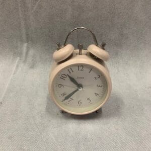 A white alarm clock sitting on top of a table.