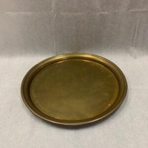 A round brass tray sitting on top of a table.