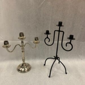 Two metal candle holders with candles on top of them.