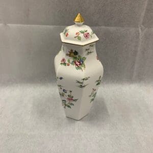 A white vase with flowers and gold top.