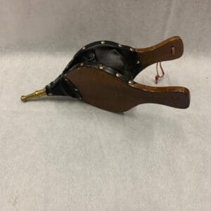 A wooden and leather duck with a handle.