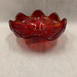 A red glass bowl sitting on top of a table.