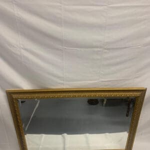 A mirror with a gold frame and white background