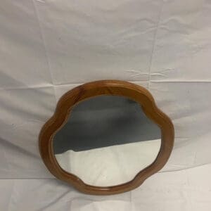 A wooden mirror sitting on top of a white sheet.