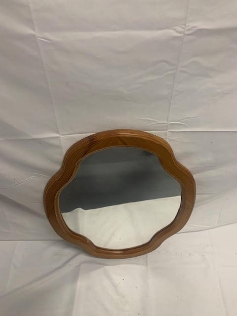 A wooden mirror sitting on top of a white sheet.