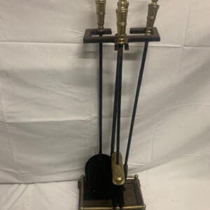 A fireplace set with three pieces of metal.