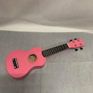 A pink ukulele is sitting on top of the floor.