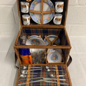 Wicker picnic basket with orange plates and cups.