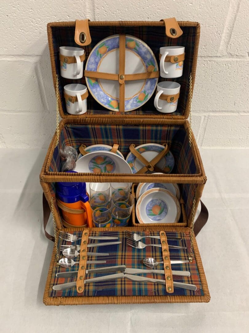 Wicker picnic basket with orange plates and cups.